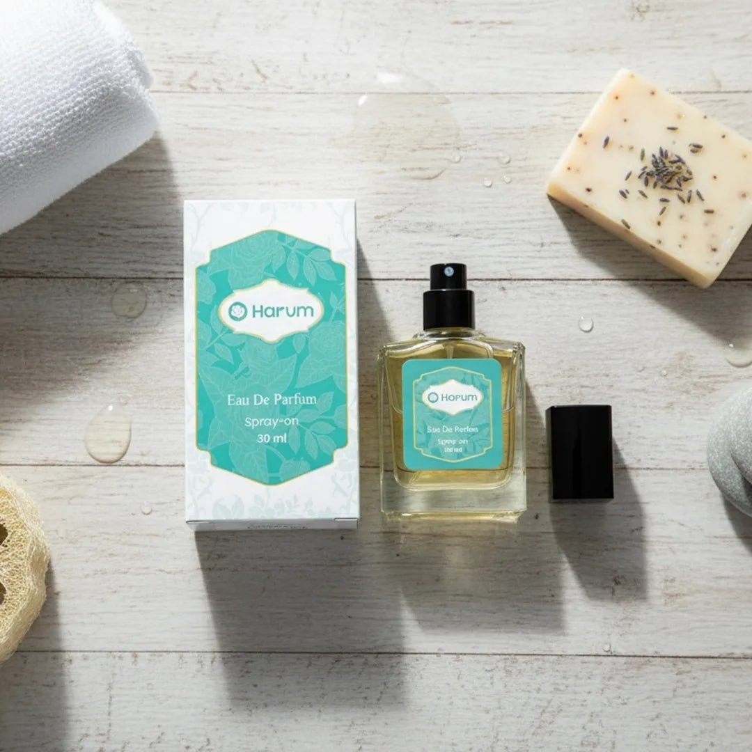 Flat lay of Harum.sg Eau De Parfum 30ml bottle and box on a wooden surface with towel, soap, and sponge, creating a clean and fresh aesthetic.