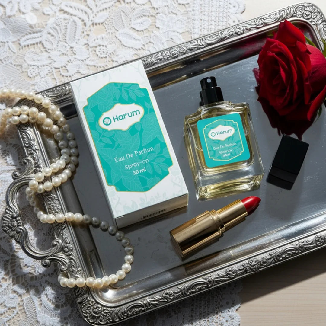 A flat lay of Harum.sg Eau De Parfum 30ml bottle and box placed on a silver tray with a red rose, pearl necklace, and red lipstick, creating a classy and romantic luxury vibe.