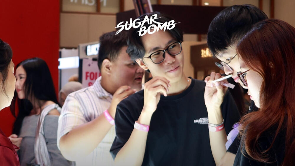 Staff helping a customer try out premium Eau De Parfum options at a SugarBomb perfume store popup event in Singapore.