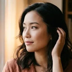 Woman with dark hair touching her ear indoors