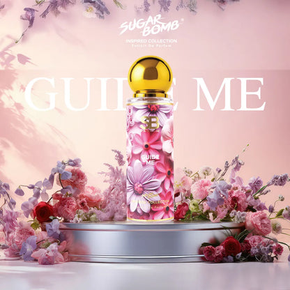 SugarBomb Guide Me Extrait De Parfum from the Inspired Collection, a luxurious woody and amber floral fragrance inspired by Amouage Guidance, showcasing a purple and pink floral pattern bottle on a silver pedestal surrounded by fresh pink roses and purple flowers.