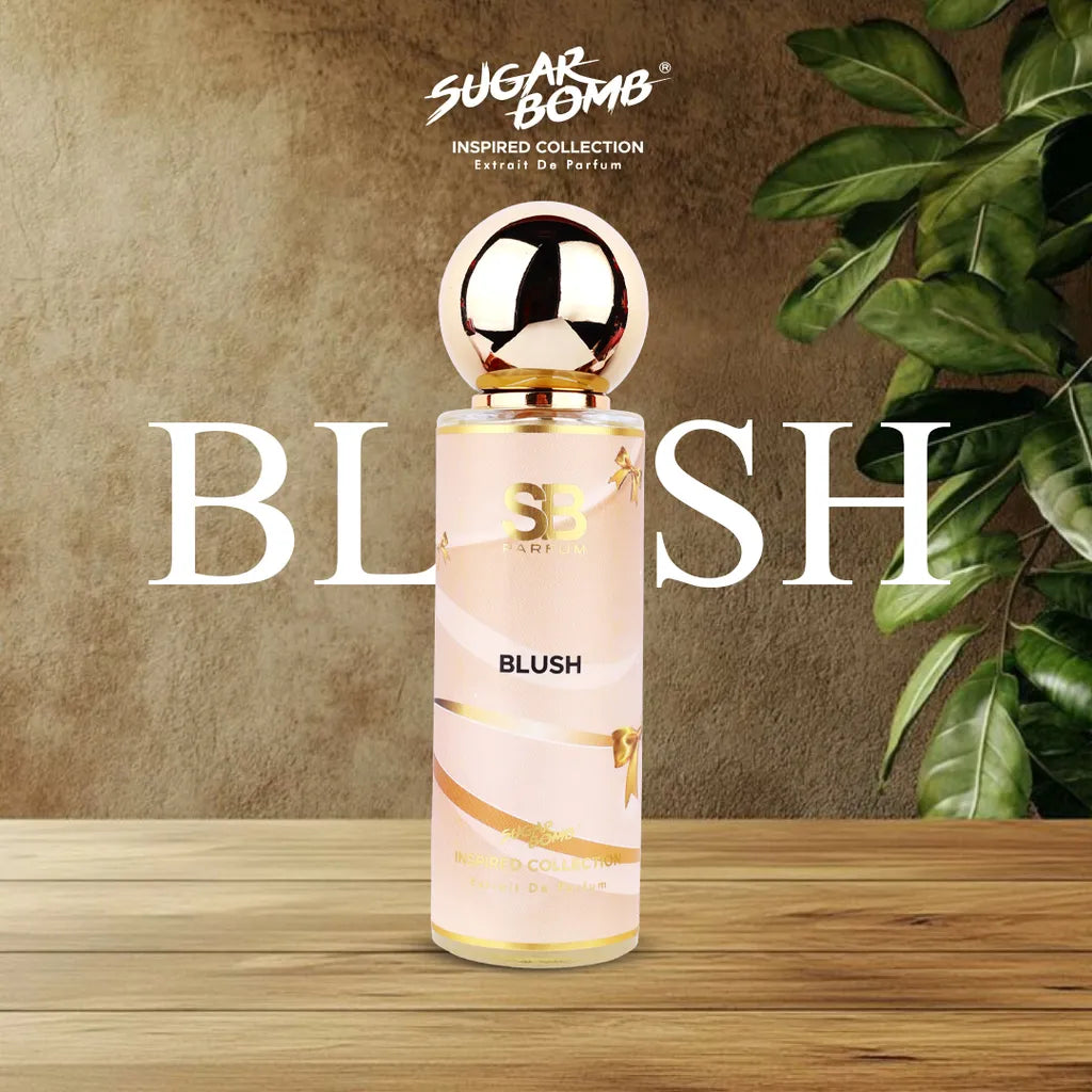 SugarBomb Blush Extrait De Parfum bottle from the Inspired Collection on a wooden surface with a concrete background.