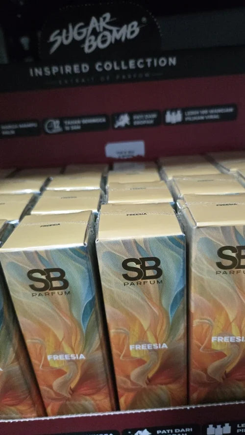 Close-up of SugarBomb (SB) Freesia perfume retail boxes in a display case, featuring floral artwork and gold branding.