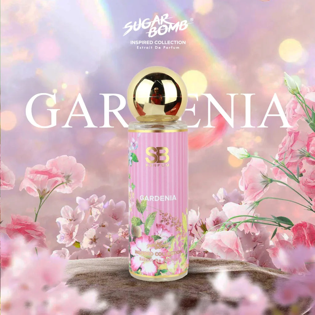 SugarBomb Gardenia Extrait De Parfum from the Inspired Collection, a sweet white floral women's fragrance inspired by Gucci Flora Gorgeous Gardenia, set on a stone pedestal amidst blooming pink flowers under a soft rainbow sky.