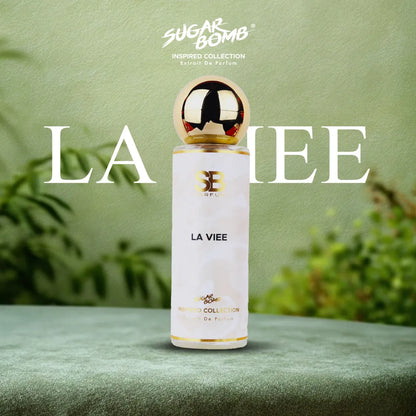 SugarBomb La Viee Extrait De Parfum from the Inspired Collection, a sweet gourmand fragrance inspired by Lancôme La Vie Est Belle, set on a soft green surface with a botanical background.