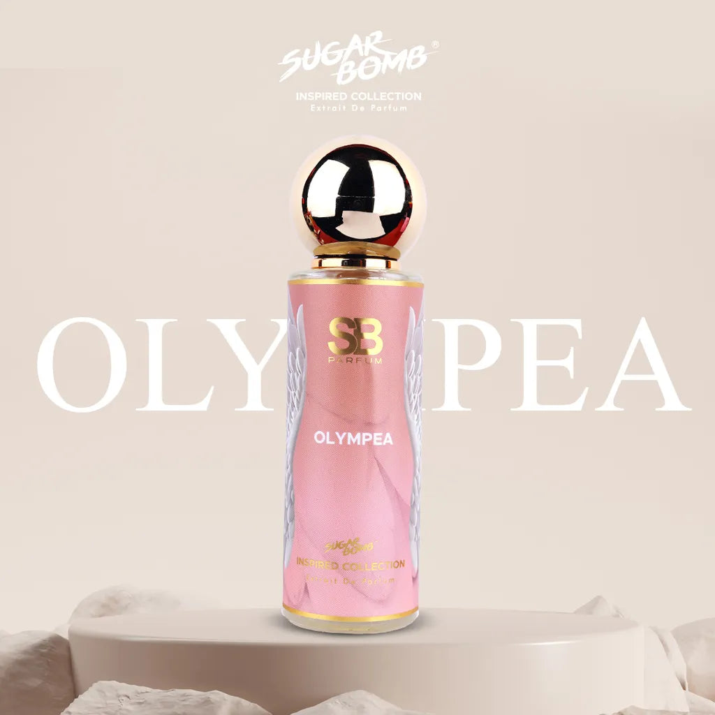 SugarBomb Olympea Extrait De Parfum from the Inspired Collection, a salted vanilla and amber women's fragrance inspired by Paco Rabanne Olympéa, featuring a pink bottle with white angel wing graphics standing on a cream pedestal surrounded by soft white stones.