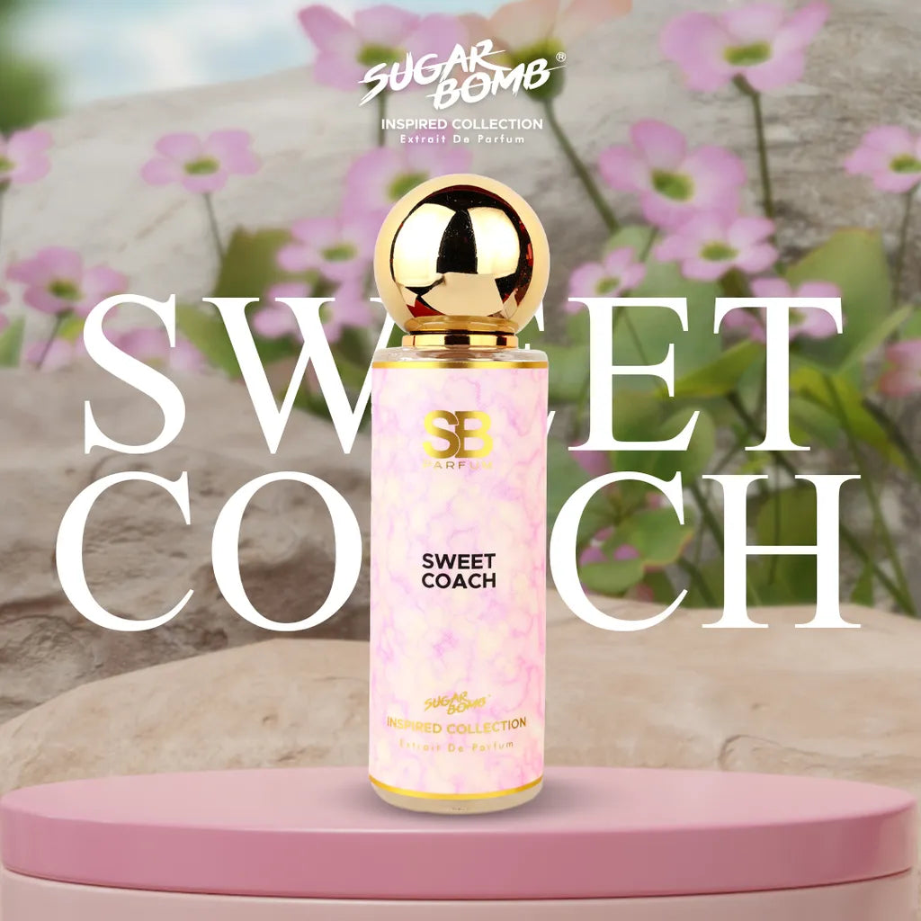 SugarBomb Sweet Coach Extrait De Parfum from the Inspired Collection, a sweet fruity-floral women's fragrance inspired by Coach, displayed on a pink pedestal with a blooming pink wildflower background.