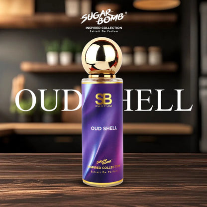 SugarBomb Oud Shell Extrait De Parfum bottle standing centered on a dark rustic wooden table. The bottle features a metallic gold spherical cap and a vibrant purple, wavy-patterned label with gold accents. The name "OUD SHELL" is overlaid in a large, clean white serif font behind the bottle. The background shows a softly blurred, warm kitchen or café interior with wooden shelves and small plants.